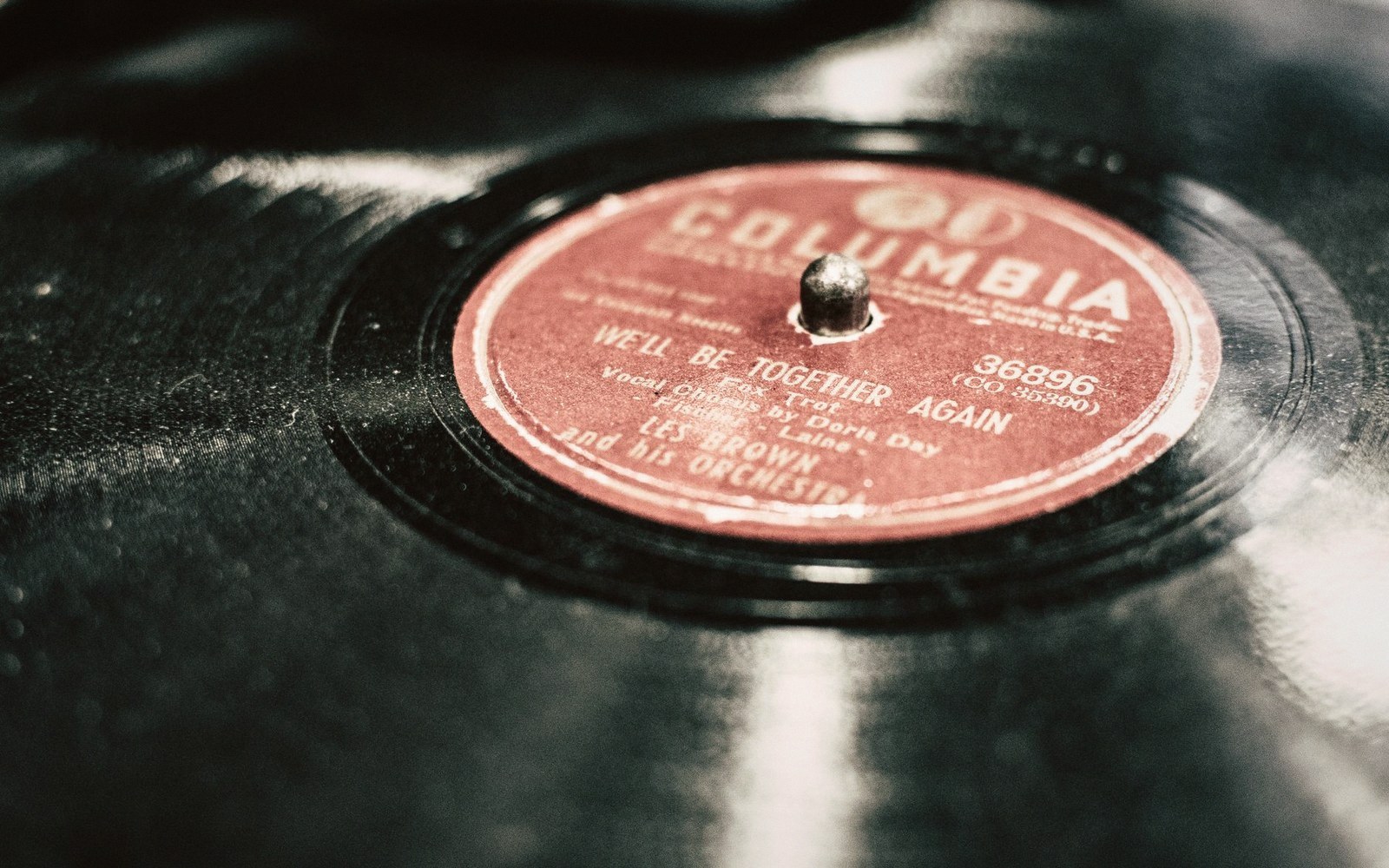 Close-up of a vinyl record spindle hole with a red Columbia label showing song and artist credits